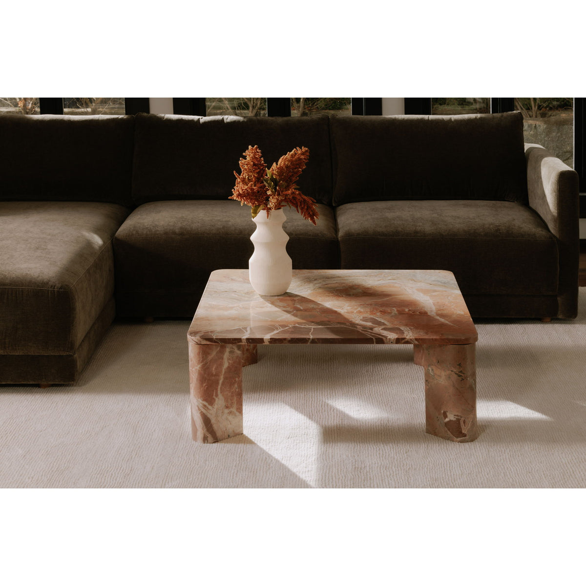 Orange marble coffee table with rectangular top and sculpted legs, vase centerpiece