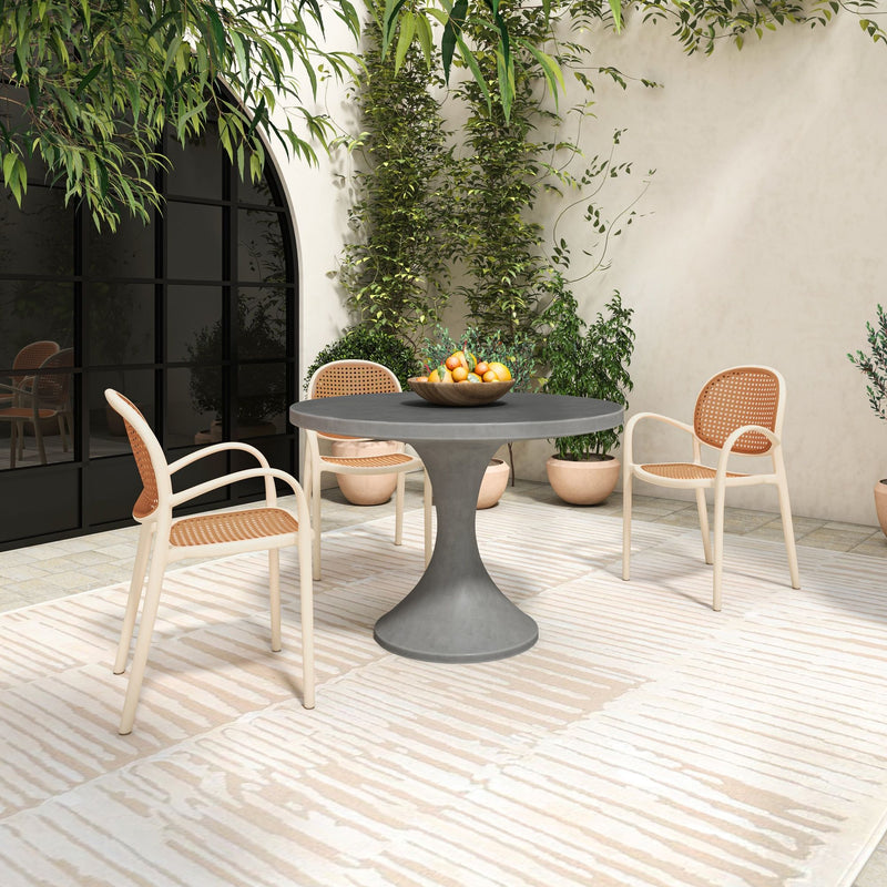 Outdoor dining table with round dark gray top and pedestal base, with chairs
