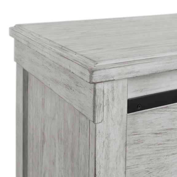 White 5-drawer chest corner close-up with cabinet edge and black drawer pull