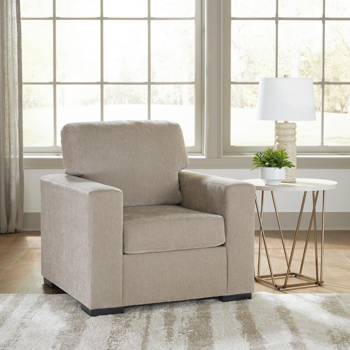 Light brown lounge chair with thick armrests and back cushion; dark legs visible below.