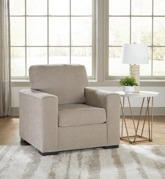 Light brown lounge chair with thick armrests and back cushion; dark legs visible below.