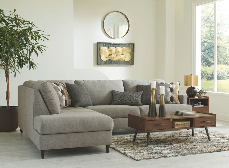 Gray sectional sofa with chaise lounge and multiple textured throw pillows.