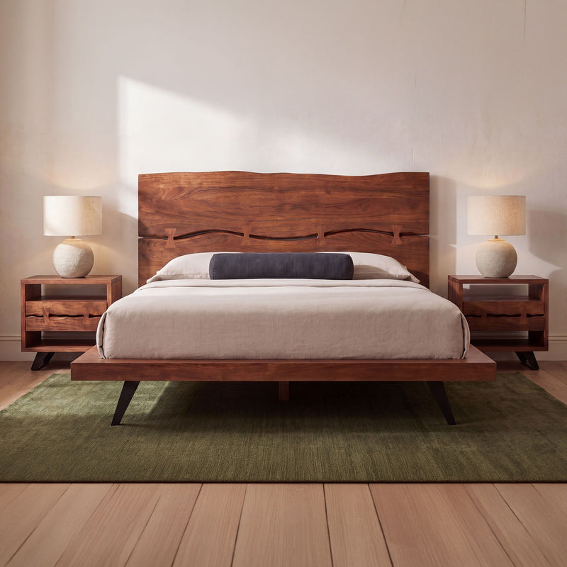 Queen platform bed with light brown wood frame, curved headboard, white bedding and pillows