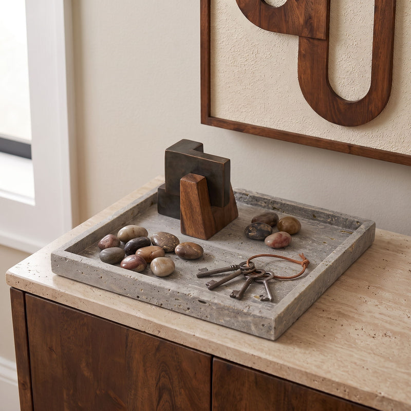 Gray speckled marble tray with raised rim, holding smooth stones and keys