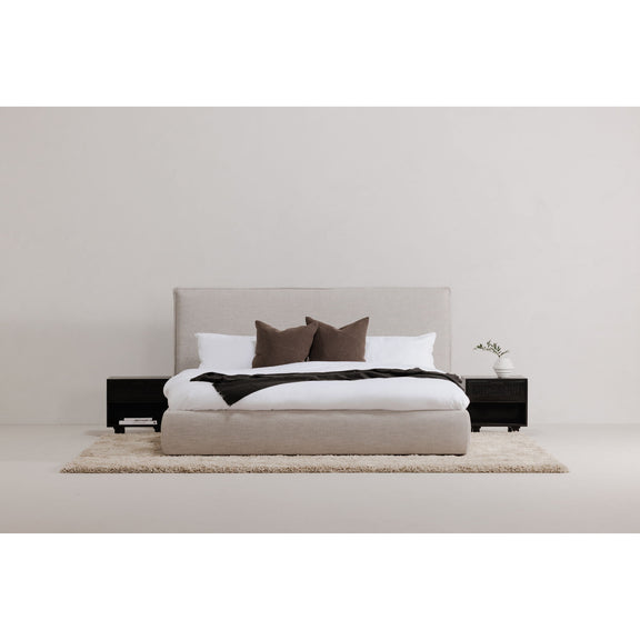 Light gray king bed with white duvet, dark pillows, and black side drawers