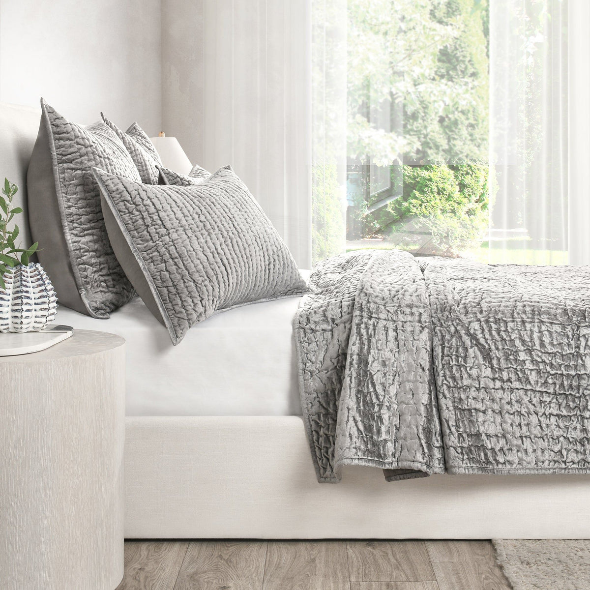 Gray velvet quilt set with textured quilt and matching shams on a sofa-bed
