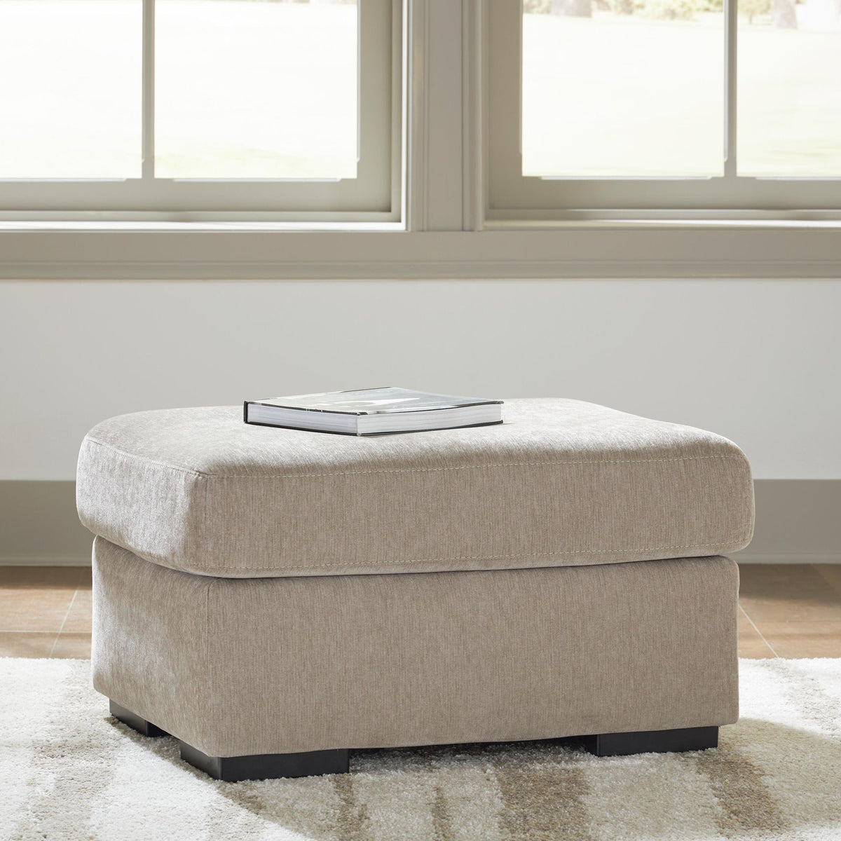 Light brown upholstered ottoman with rounded seat and dark legs