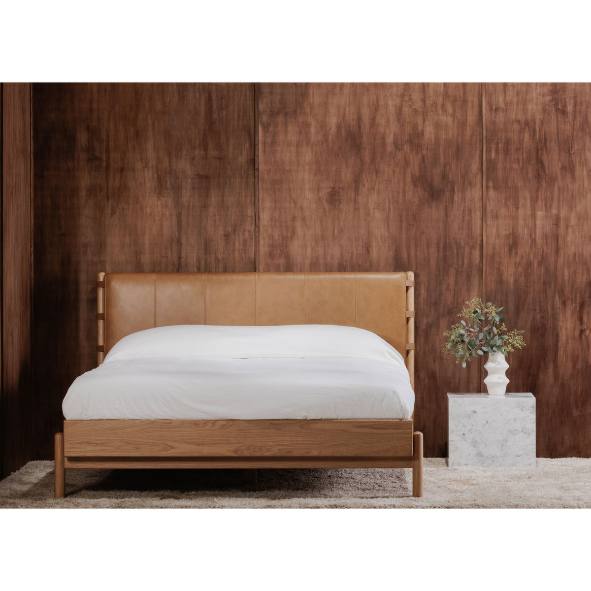 Queen bed with brown upholstered headboard and light wood frame, white bedding