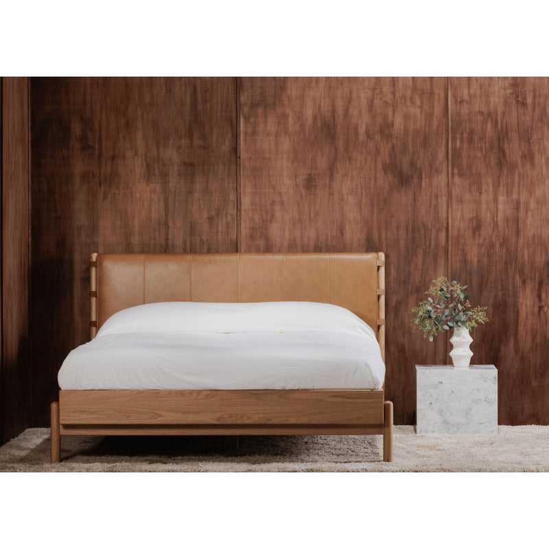 Queen bed with brown upholstered headboard and light wood frame, white bedding