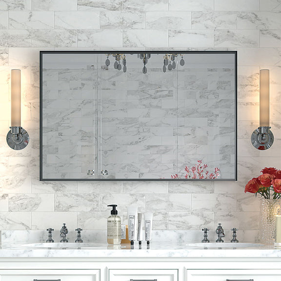 Rectangular bathroom mirror with dark frame against light marble tile wall.