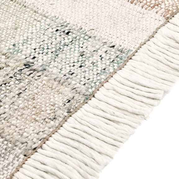 Ritsa rug corner close-up with textured patchwork and long white fringe trim