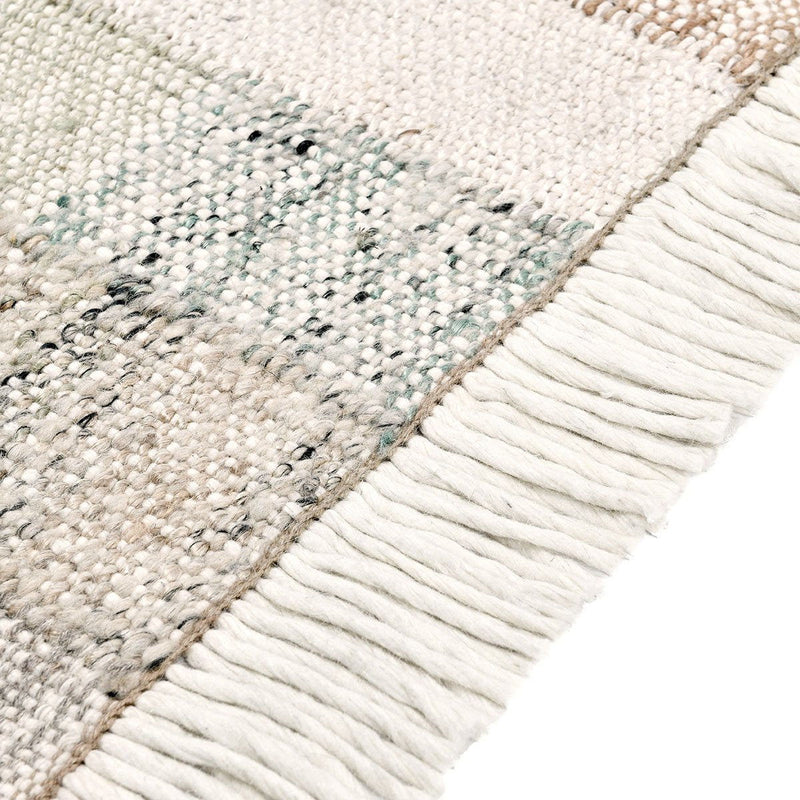 Ritsa rug corner close-up with textured patchwork and long white fringe trim