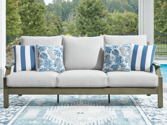 Gray sofa with brown frame, four blue patterned cushions and center lumbar pillow