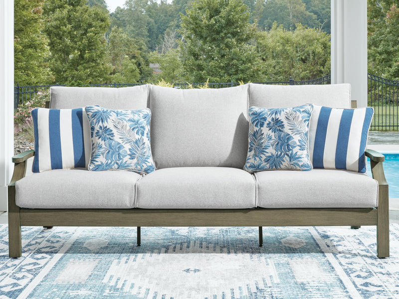 Gray sofa with brown frame, four blue patterned cushions and center lumbar pillow