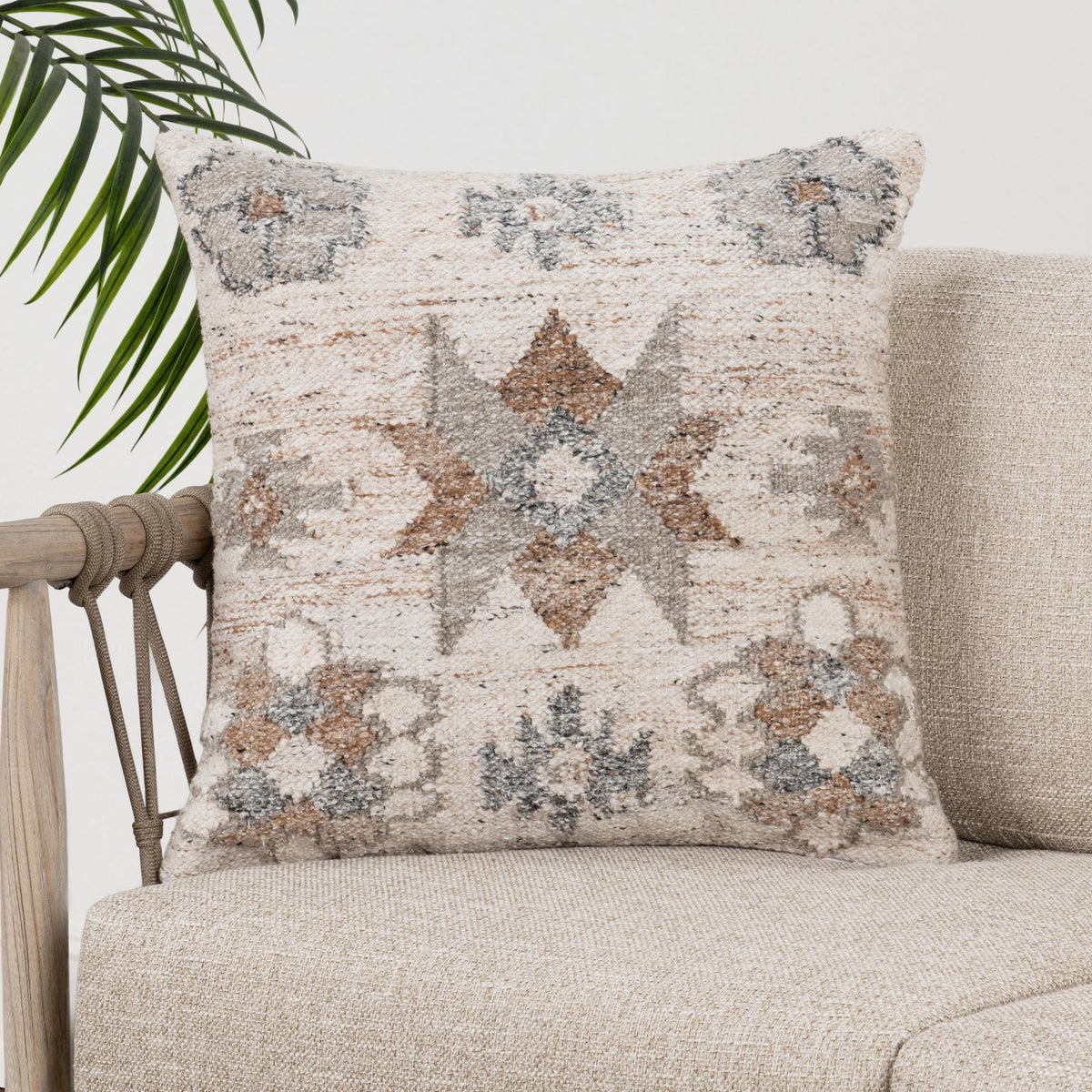 Geometric patterned square pillow with cream, gray, and clay tones