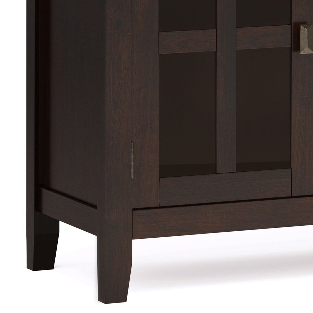 Sideboard corner detail showing dark wood grain, glass door frame, metal pull, and tapered leg