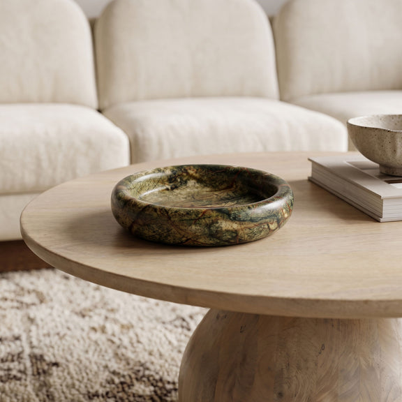 Green marble round tray on a wooden coffee table with visible stone veining.