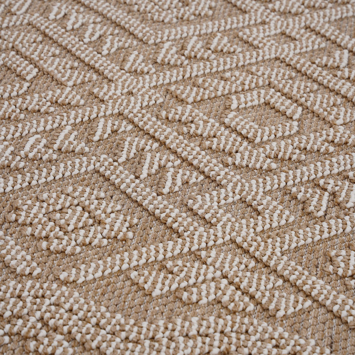 Light brown rug close-up with raised looped texture and repeating geometric motif.