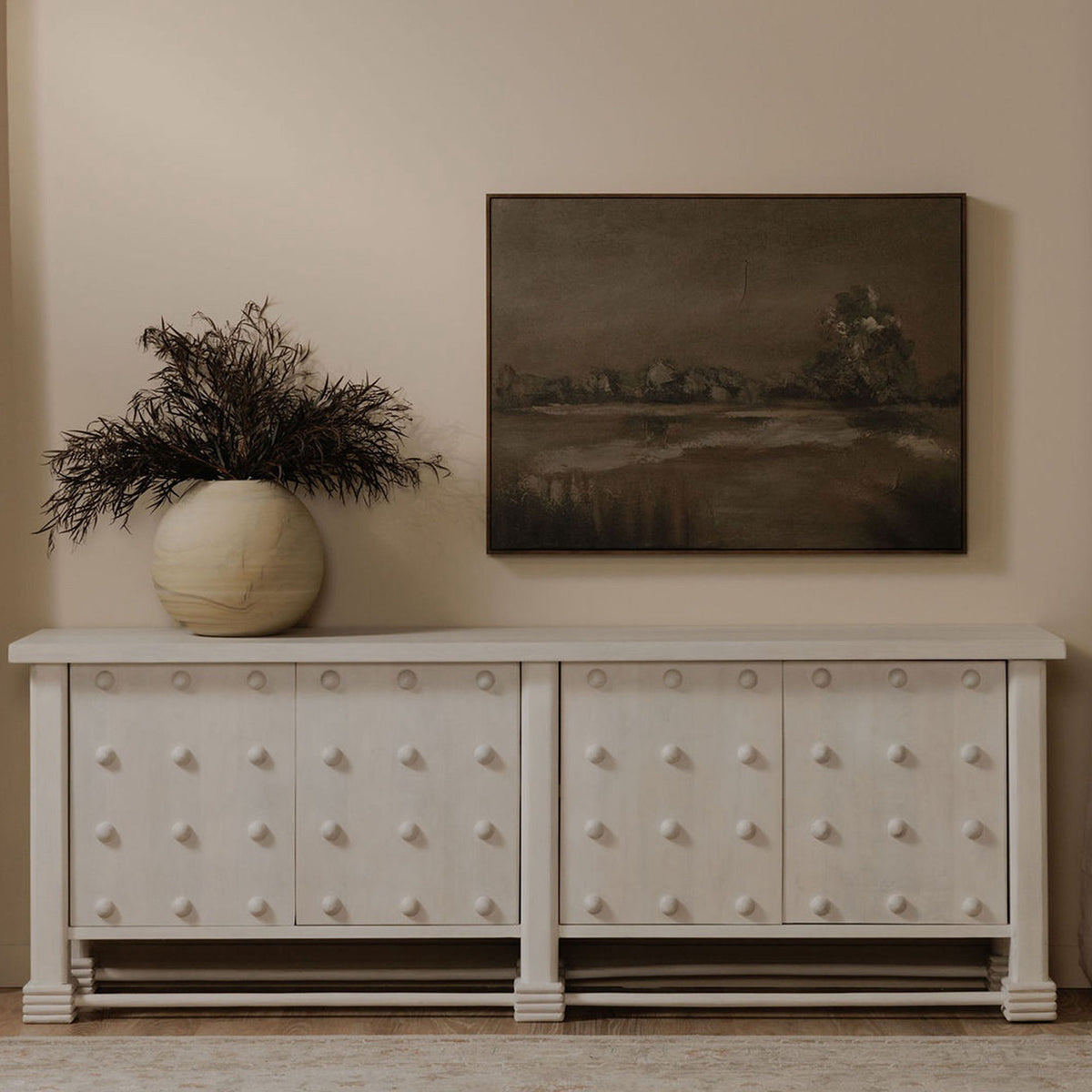 Framed landscape wall art in dark tones, hung above a white cabinet