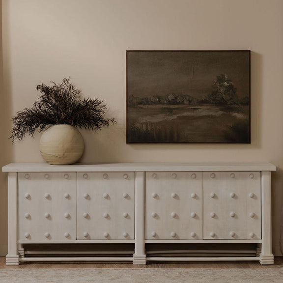 Framed landscape wall art in dark tones, hung above a white cabinet