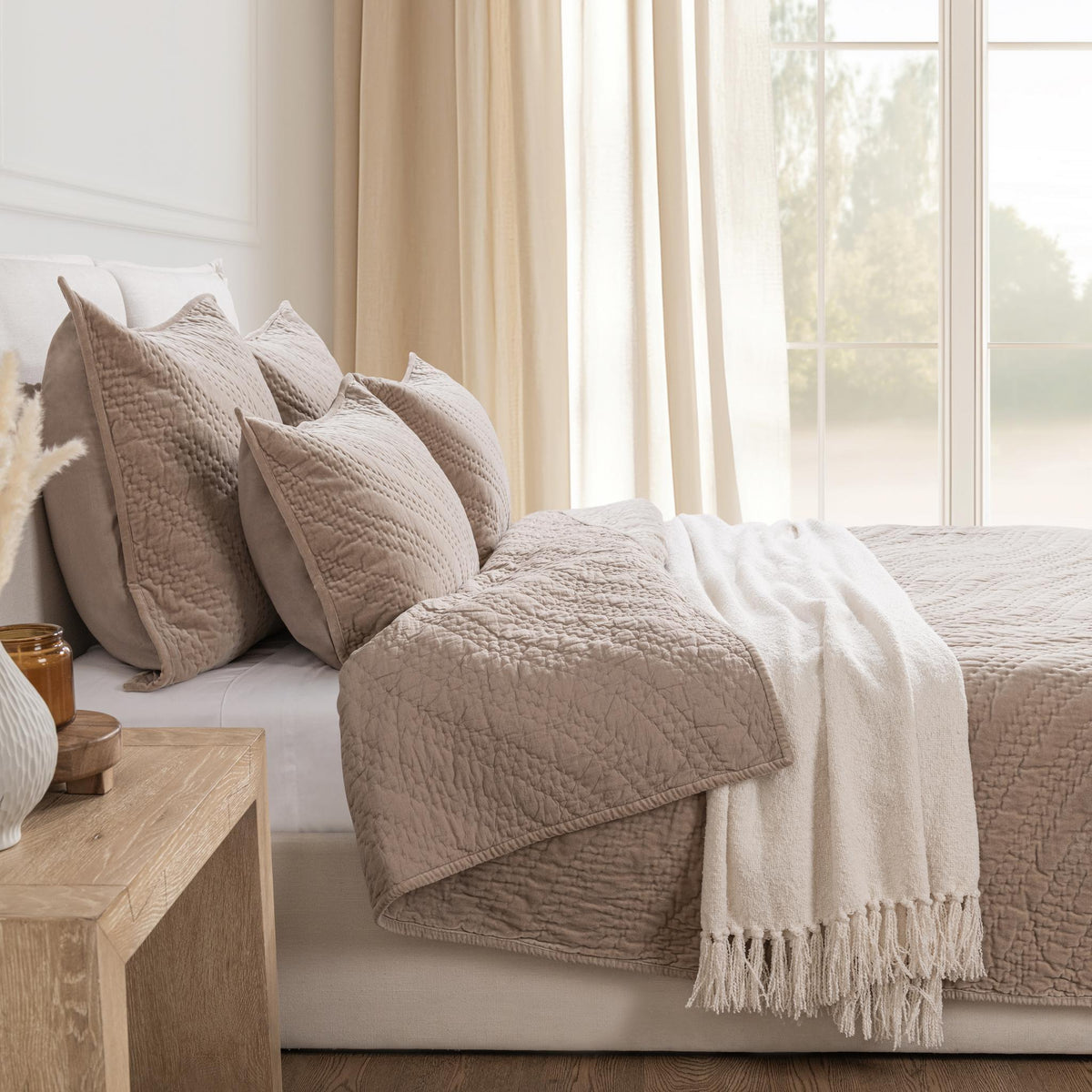 Beige velvet bedding set with matching pillows and fringed throw on bed