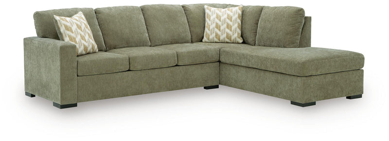 Sleeper sectional sofa with corner chaise, dark green upholstery, two patterned accent pillows