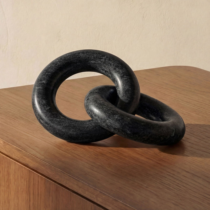 Black tabletop decor knot sculpture with interlocking rings on a wooden table