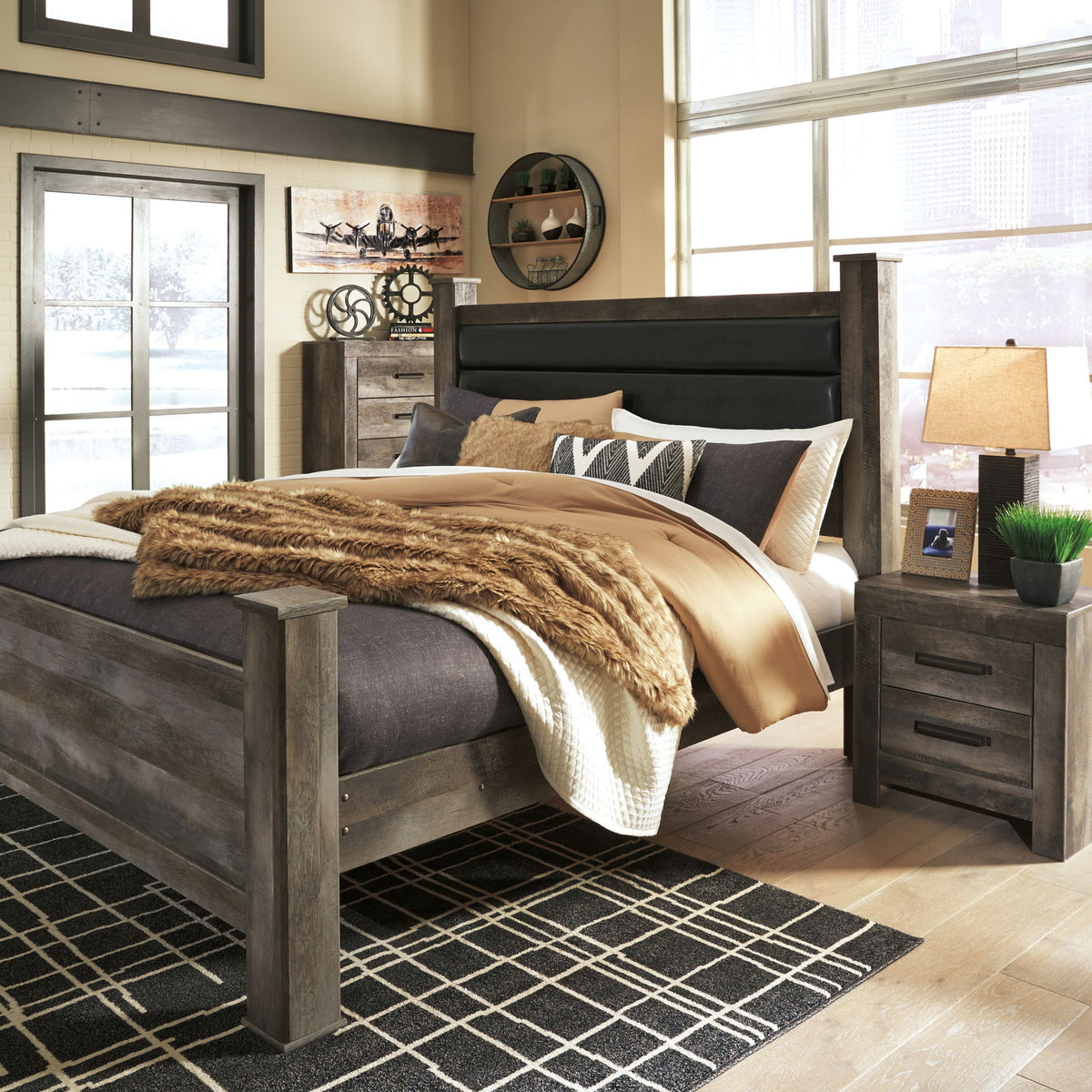 Gray upholstered poster bed with tall headboard, made with pillows and knit throw