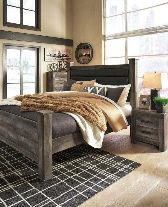 Gray upholstered poster bed with tall headboard, made with pillows and knit throw