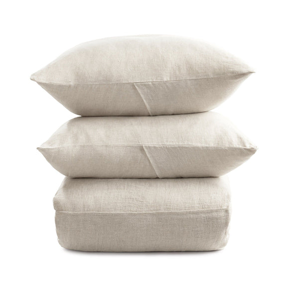 Light beige linen pillow shams stacked, showing seams and envelope-style back