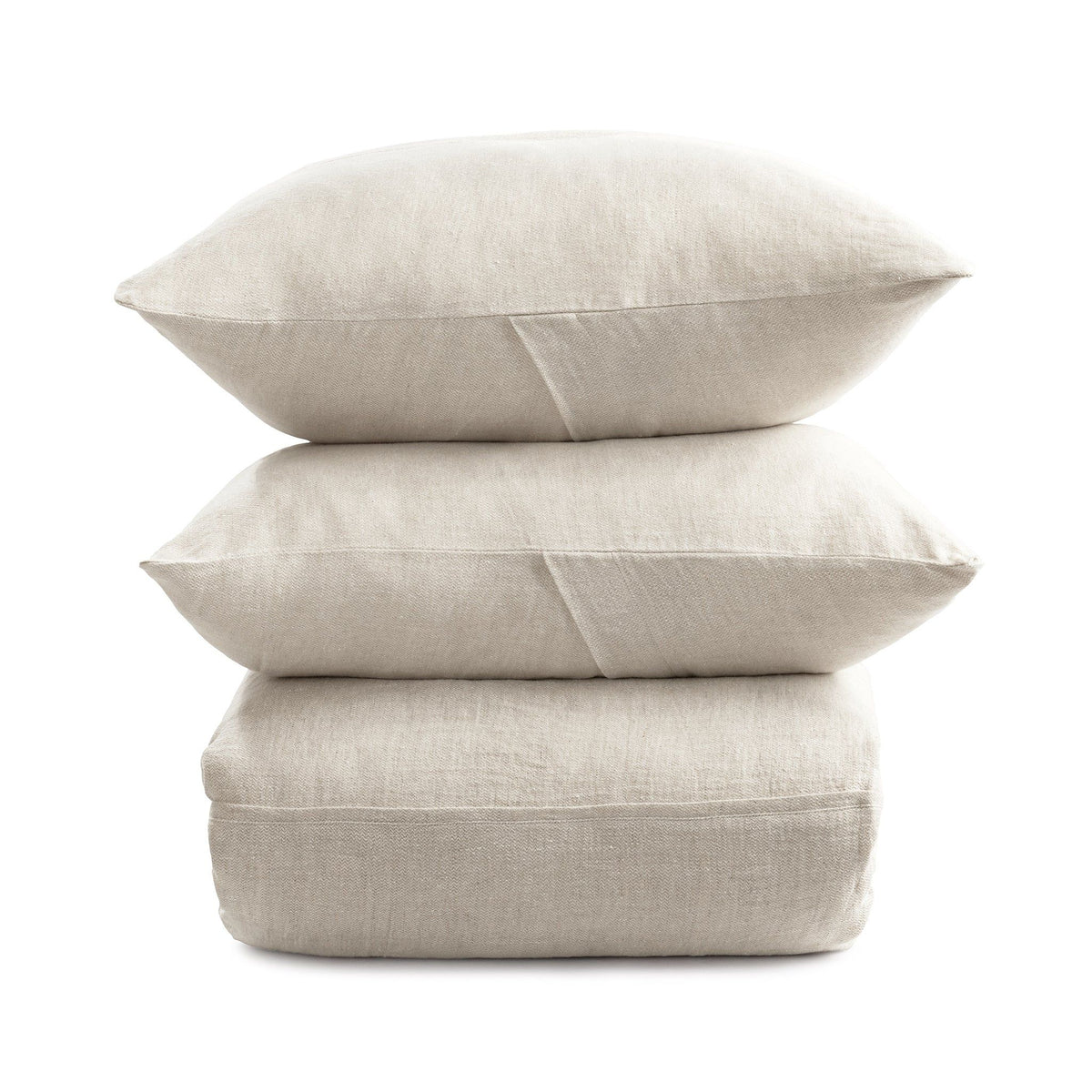 Stacked beige duvet and pillows bundle on a plain background