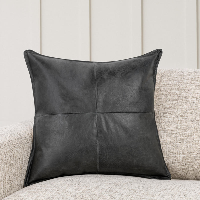 Black leather decorative pillow with central seam and piped edges