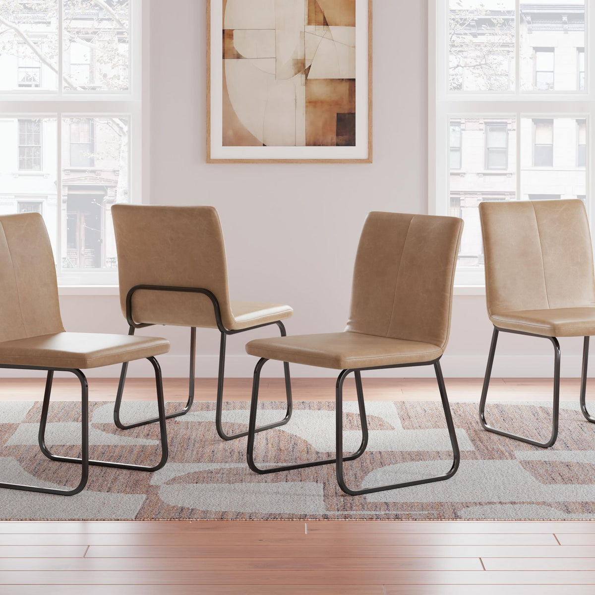 Four tan upholstered dining side chairs with curved backs and black metal sled legs