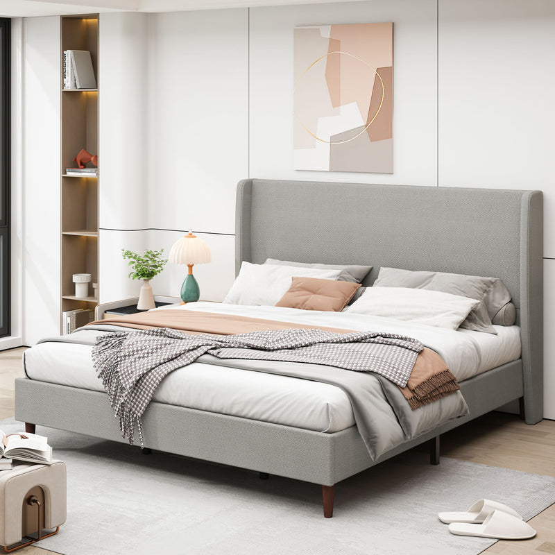 Gray upholstered bed with tall headboard, pillows, and layered bedding