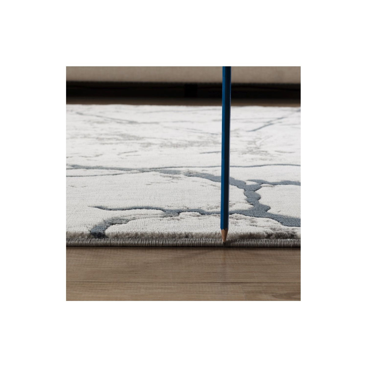 Gray area rug corner with abstract blue-gray vein pattern and low pile