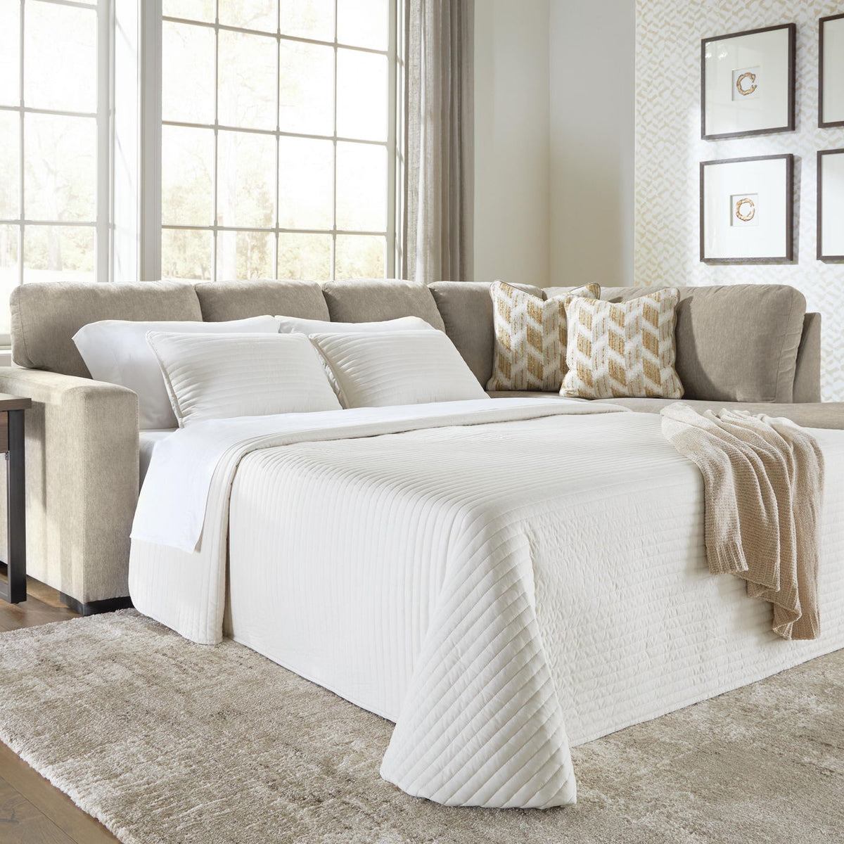 Gray sleeper sectional sofa opened into a bed with white bedding
