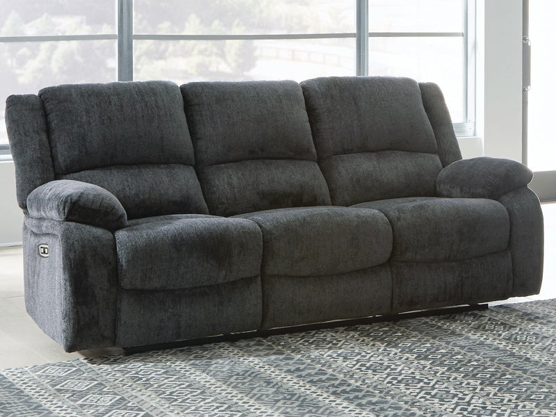 Dark gray reclining sofa with padded arms and three back cushions, side angle