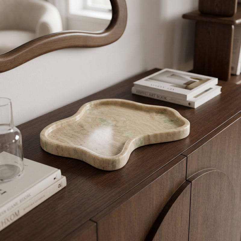 Beige marble tray on a tabletop, leaf-like design with shallow recessed surface.