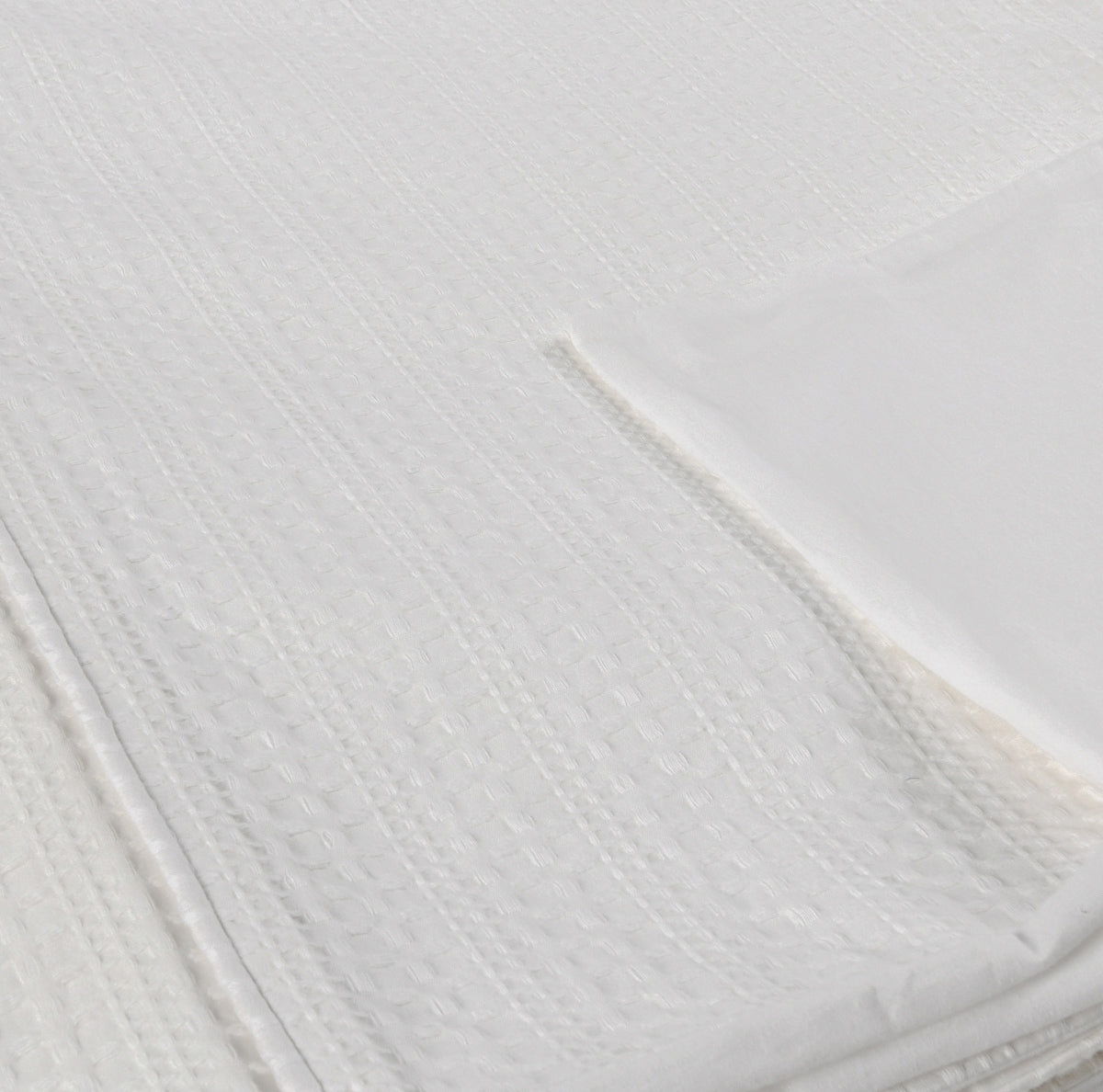 Closeup of white woven pillow sham fabric with textured diamond pattern