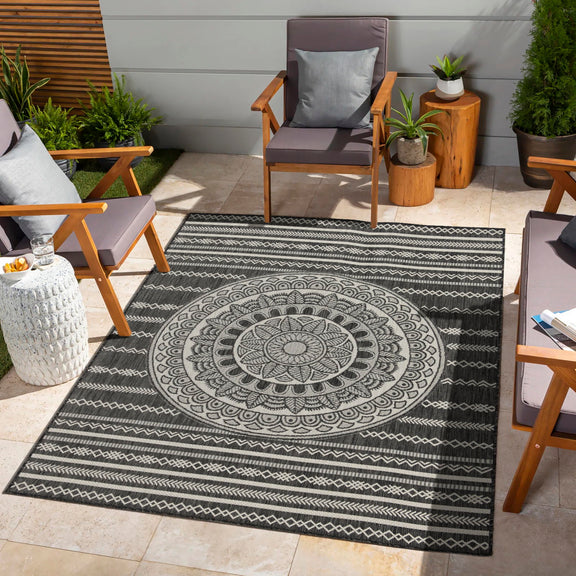 Indoor/outdoor area rug with dark blue mandala center, zigzag border, and geometric bands