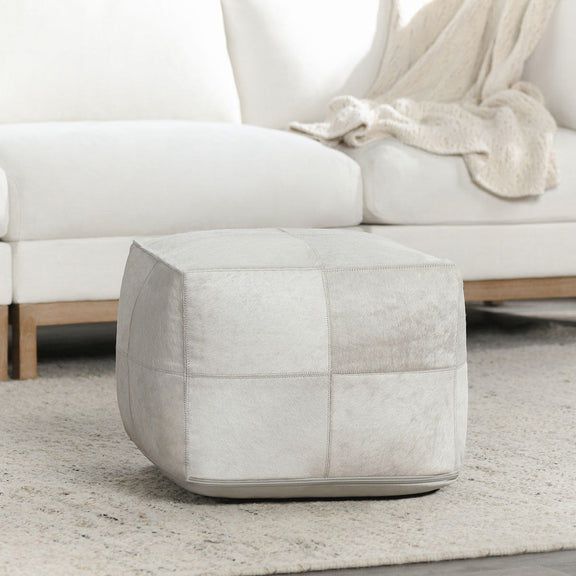 Ivory hide pouf on rug with stitched panels and rounded top