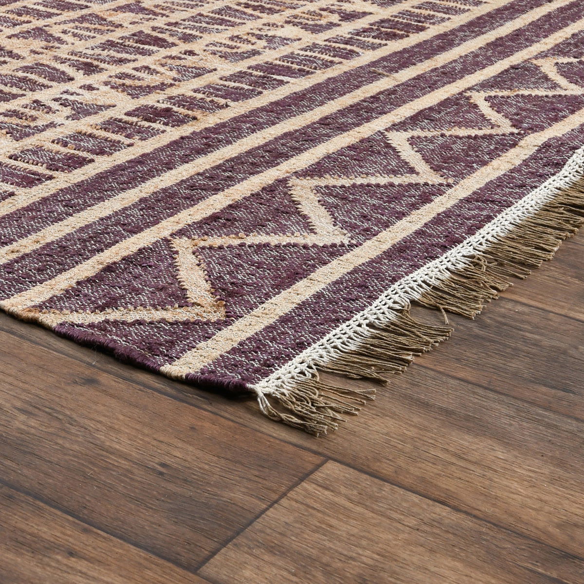 Distressed rug detail with purple geometric zigzags, cream stripes, and short fringe