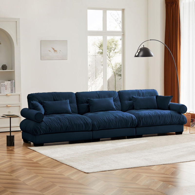 Dark blue oversized sofa with tufted back cushions, rounded bolster arms, and throw pillows