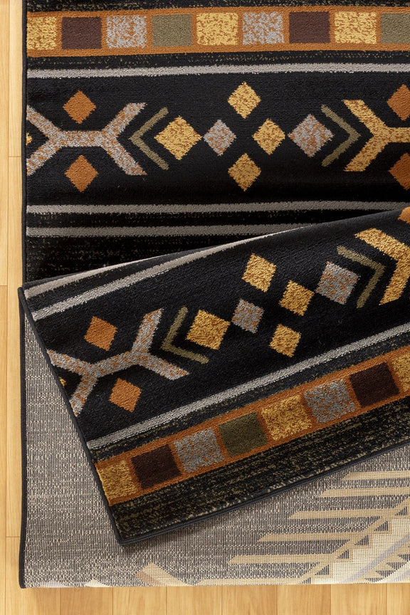 Southwest area rug with black base, tan and gold geometric motifs and zigzag border
