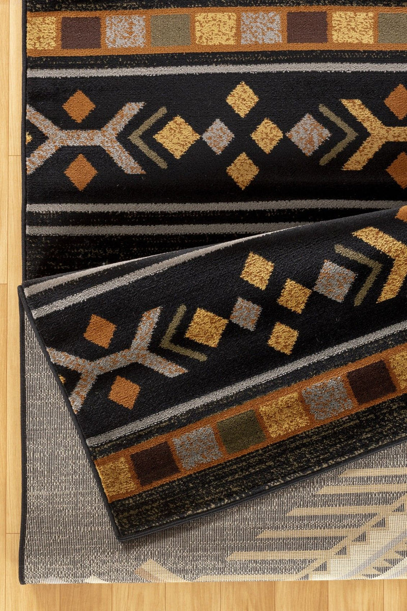 Southwest area rug with black base, tan and gold geometric motifs and zigzag border
