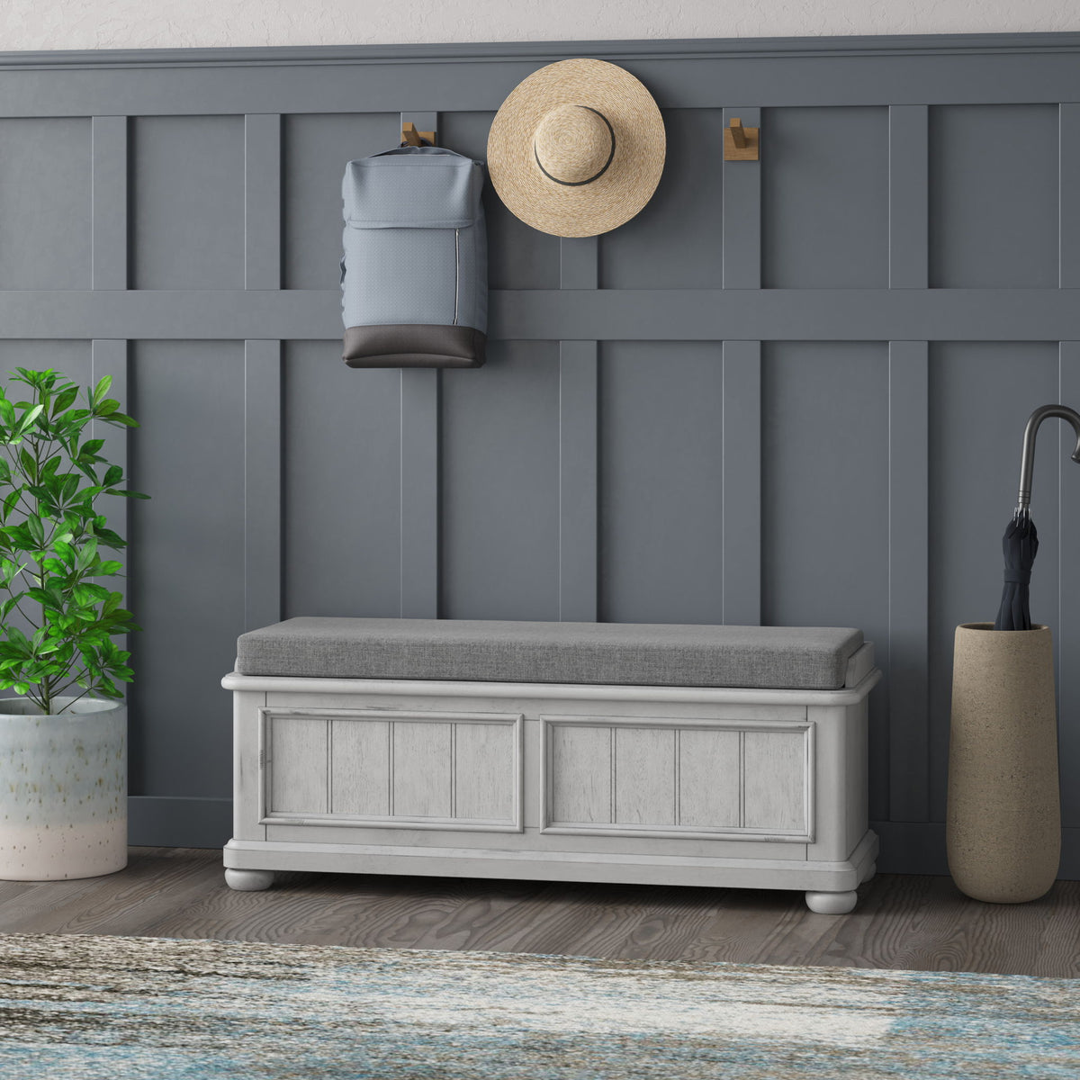 Gray cushioned storage bench with paneled cabinet doors and white base trim