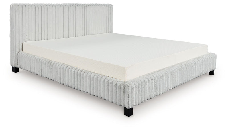 Light gray upholstered bed frame with ribbed headboard, white mattress and bedding.