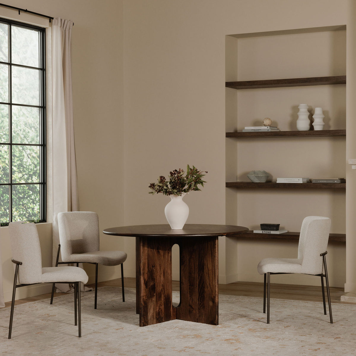 Beige upholstered dining chairs with slim dark metal legs around a dining table