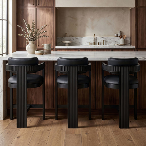 Three black vegan leather counter stools with fluted backs and black frames