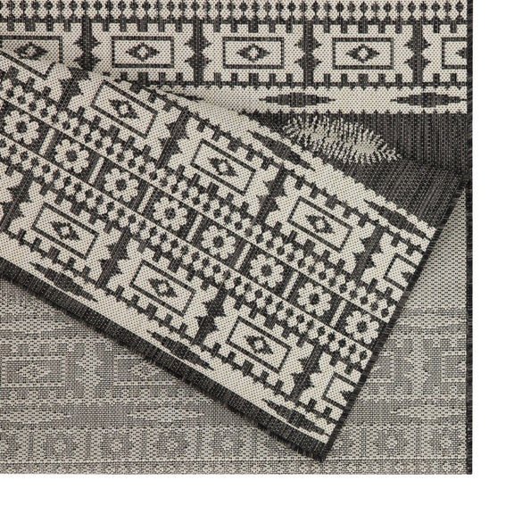 Close-up of gray and black polypropylene rug with woven geometric blocks pattern